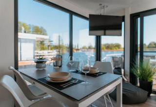 Zona pranzo su houseboat a Zehdenick con vista sull’acqua, grandi finestre e arredo moderno.