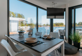 Zona pranzo su houseboat a Zehdenick con vista sull’acqua, grandi finestre e arredo moderno.