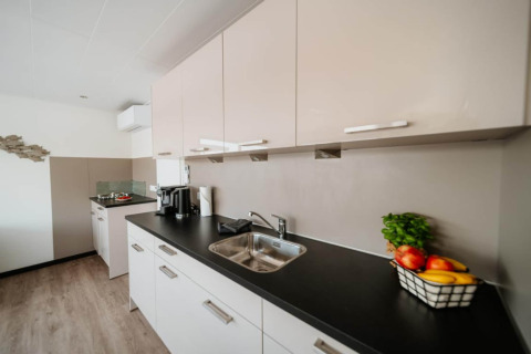 Modern kitchen on houseboat in Zehdenick with black countertop, fruit basket, sink, and coffee maker.