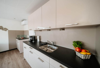 Cucina moderna su houseboat a Zehdenick con piano nero, lavello, macchina da caffè e frutta.