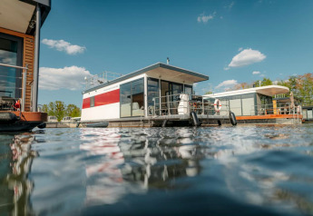 Moderne woonboot in Zehdenick op het water, omgeven door andere woonboten bij heldere lucht.