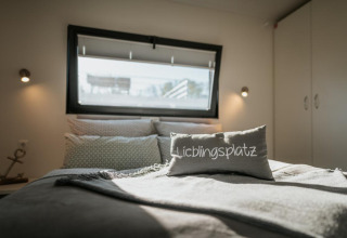 Bedroom on a houseboat in Zehdenick featuring a 'Lieblingsplatz' pillow and soft sunlight from window.