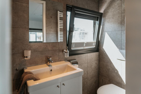 Modern bathroom on a houseboat in Zehdenick with a sink, mirror, open window, and natural light.