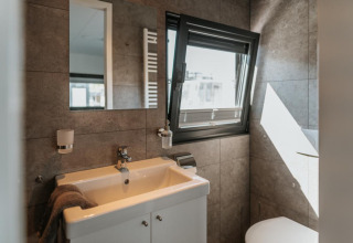Modern bathroom on a houseboat in Zehdenick with a sink, mirror, open window, and natural light.