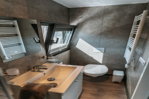 Modern, compact bathroom with mirror, sink, toilet, and window on a houseboat in Zehdenick, well lit.