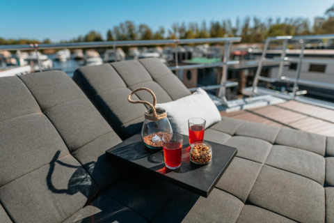 Relaxing outdoor lounge area on a houseboat in Zehdenick with drinks, snacks, and a view of the water.