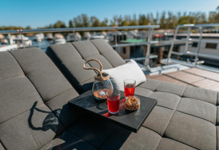 Relaxing outdoor lounge area on a houseboat in Zehdenick with drinks, snacks, and a view of the water.