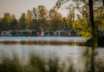 Woonboten liggen aangemeerd op een kalme vijver in Zehdenick, omgeven door groene bomen.