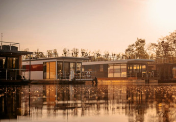 Moderne Hausboote spiegeln sich im ruhigen Wasser bei Sonnenuntergang, Houseboat «in Zehdenick», Deutschland.