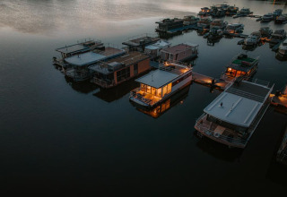 Aerial view of houseboats at Houseboat in Zehdenick, some warmly lit and floating peacefully at dusk.