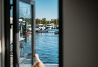 Uitzicht vanuit Houseboat in Zehdenick via een open deur op aangemeerde boten in de jachthaven.