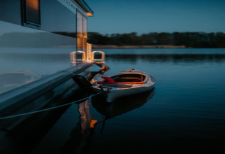 Kayak ormeggiato a una houseboat su acqua calma al tramonto, Houseboat a Zehdenick.