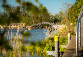 Zicht op rivier met brug, aanlegsteiger en groene oevers bij Houseboat in Zehdenick op een zonnige dag.