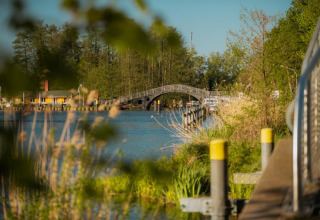 Vista sul fiume con ponte, molo e vegetazione vicino a Houseboat a Zehdenick in una giornata di sole.