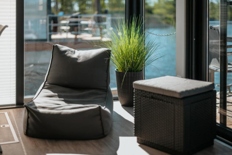 Area lounge moderna su houseboat a Zehdenick con poltrona sacco, pouf e pianta vicino alla finestra.