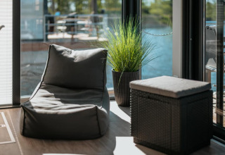 Area lounge moderna su houseboat a Zehdenick con poltrona sacco, pouf e pianta vicino alla finestra.
