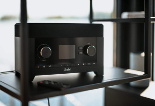 Radio Teufel nera con telecomando su mensola in una moderna houseboat a Zehdenick con ampia finestra.