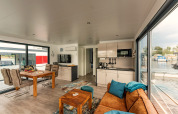 Modernes Wohnzimmer und Küche auf einem Hausboot in Zehdenick mit Panoramablick aufs Wasser.