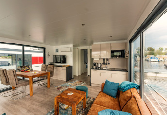 Licht en modern interieur van een woonboot in Zehdenick met zicht op het water door grote ramen.