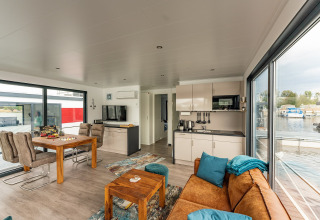 Interior moderno y luminoso de una casa flotante en Zehdenick con grandes ventanales y vistas al agua.