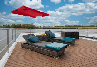 Sun deck on Houseboat in Zehdenick with loungers, red umbrella, and scenic water and nature view.