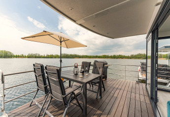 Terras op een woonboot in Zehdenick met tuintafel, stoelen, parasol en prachtig meerzicht.