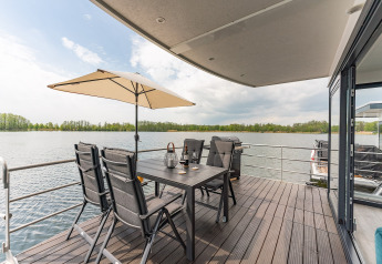 Terras op een woonboot in Zehdenick met tuintafel, stoelen, parasol en prachtig meerzicht.