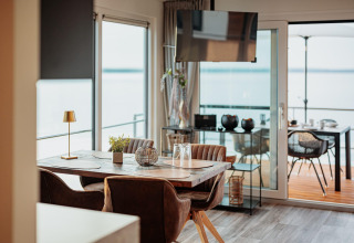 Zona pranzo moderna su una houseboat al Gräbendorfer See, vista lago e terrazza esterna visibili.