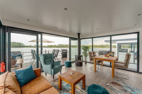 Sala de estar moderna y luminosa en una casa flotante en Zehdenick con grandes ventanas al lago.