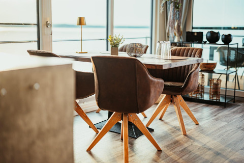 Modern dining area with brown chairs and wooden table on Houseboat am Gräbendorfer See overlooking the lake.
