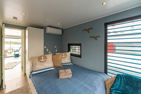 Bedroom on houseboat in Zehdenick featuring blue walls, double bed, window, and terrace view.