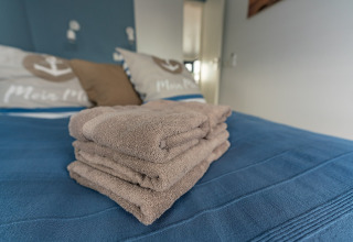 Netjes gevouwen handdoeken op een bed met blauw dekbed op de Houseboat in Zehdenick, huiselijke sfeer.