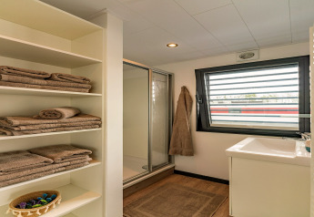 Modernes Hausboot-Badezimmer in Zehdenick mit Handtüchern, Dusche und großem Fenster.