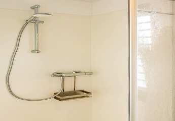 Moderne douche met chromen kranen in de badkamer van de woonboot in Zehdenick, Duitsland.