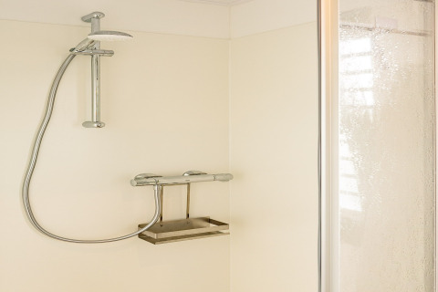 Moderne douche met chromen kranen in de badkamer van de woonboot in Zehdenick, Duitsland.