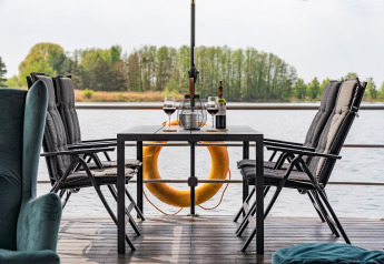 Eettafel met wijn en glazen op een woonboot in Zehdenick, met zicht op water en bomen.
