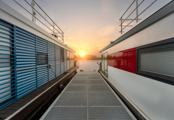 Zonsondergang tussen twee moderne woonboten bij Houseboat in Zehdenick, uitzicht vanaf de steiger.