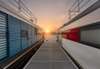 Sunset view between two modern houseboats at Houseboat in Zehdenick, looking along a dock.