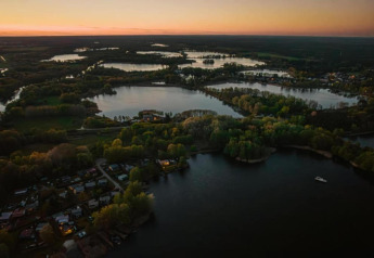 Vue aérienne d'un houseboat à Zehdenick, Allemagne, entouré de lacs et de verdure au coucher du soleil.