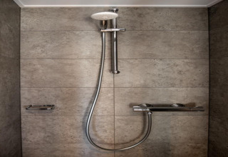 Moderne douche met grijze tegels en chromen armaturen op een woonboot in Zehdenick, Duitsland.