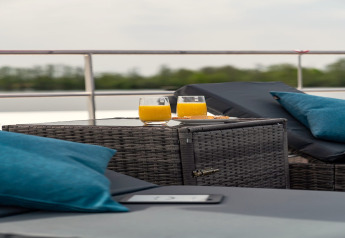 Zwei Gläser Orangensaft und Kekse auf einem Tisch auf einem Hausboot mit blauen Kissen in Zehdenick.