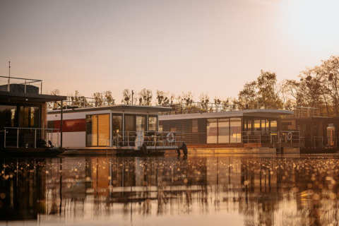 Houseboat «in Zehdenick» sull'acqua calma al tramonto, circondata dalla natura in Germania.