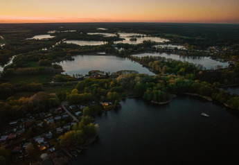 Luftfoto af houseboat ved søen i Zehdenick, Tyskland, omgivet af frodig natur ved solnedgang.