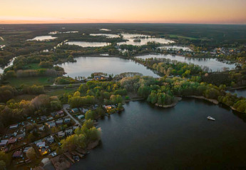 Luchtfoto bij zonsondergang van Houseboat «in Zehdenick» op een meer omringd door bossen in Duitsland.