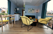 Moderne woonkamer op Houseboat Friedrich met gele stoelen, eettafel en grote ramen met uitzicht.