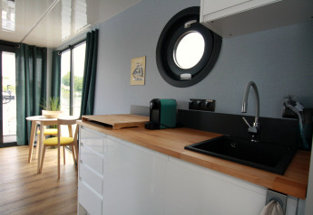 Modern kitchen and dining area on Houseboat Friedrich featuring a round porthole, wood countertop and window.