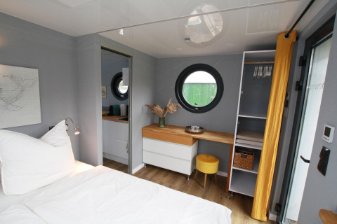 Camera accogliente sulla Houseboat Friedrich con finestra rotonda, scrivania e arredo moderno.