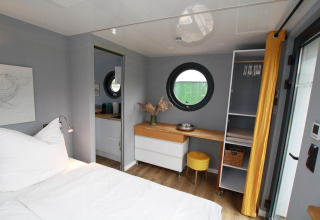 Camera accogliente sulla Houseboat Friedrich con finestra rotonda, scrivania e arredo moderno.