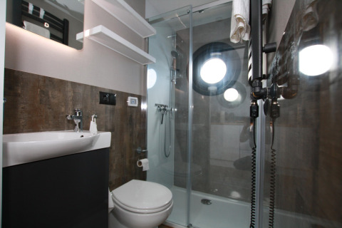 Moderne badeværelse med bruser og runde koøjevinduer på Houseboat Friedrich, minimalistisk stil.
