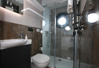 Bagno moderno con doccia e oblò rotondi sulla Houseboat Friedrich, design contemporaneo e raffinato.